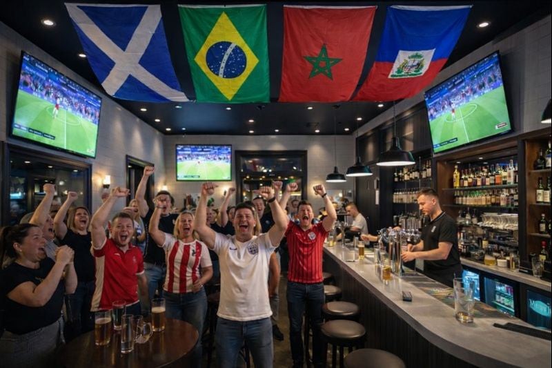 People in a bar watching sports on multiple screens with Scotlands World Cup groups flags above.